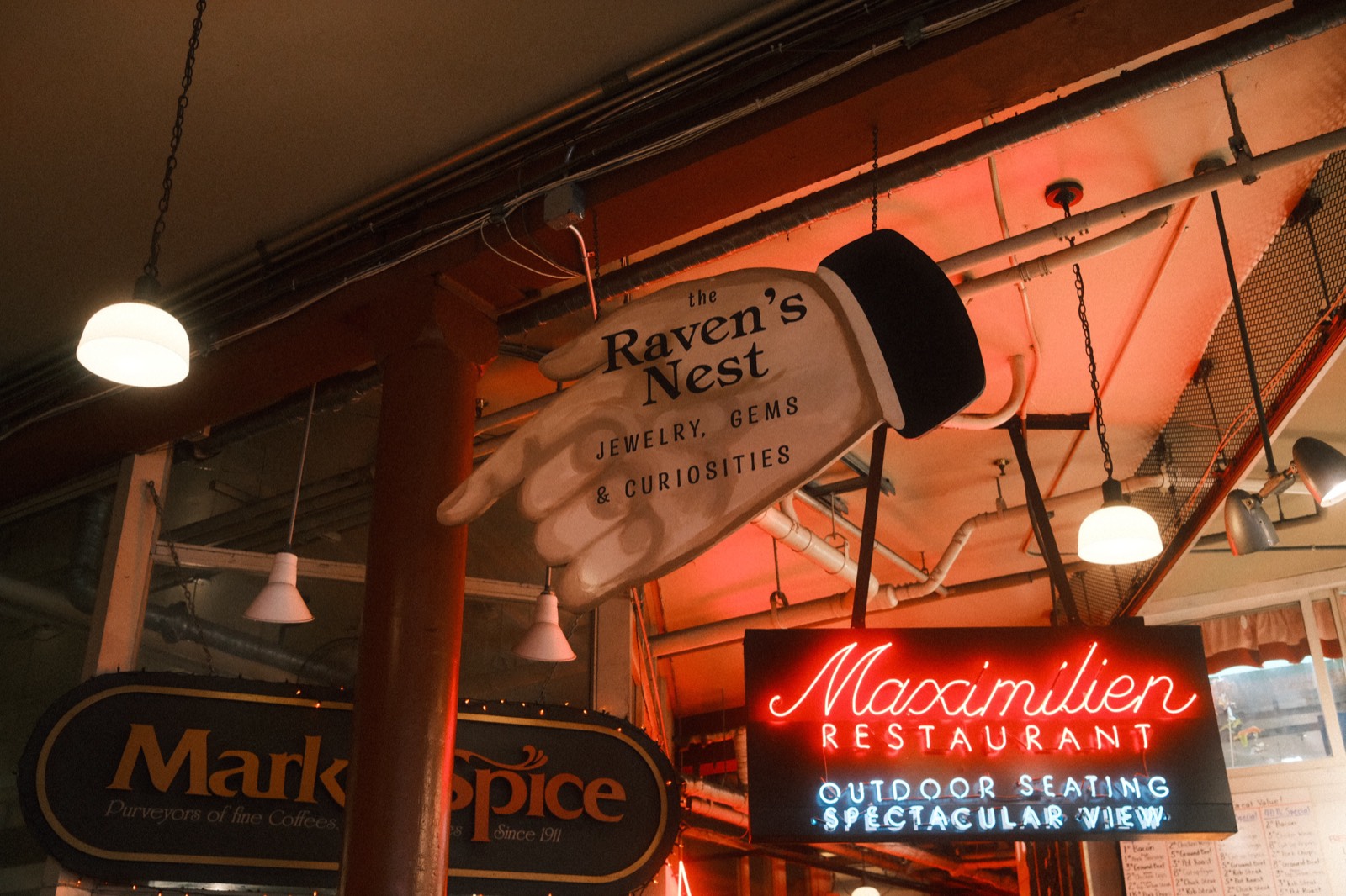 The carved 'Raven's Nest — Jewelry, Gems & Curiosities' sign hanging in Pike Place Market — look for this